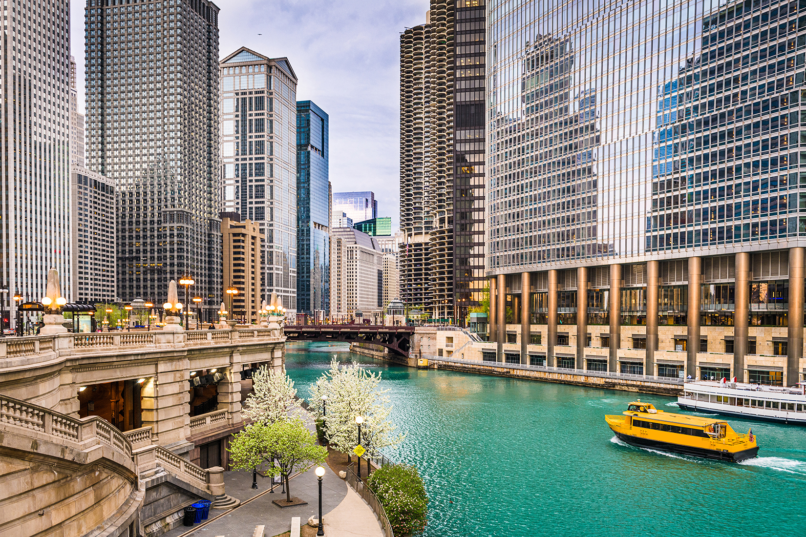 A boat traveling down a river next to tall buildings in Chicago.