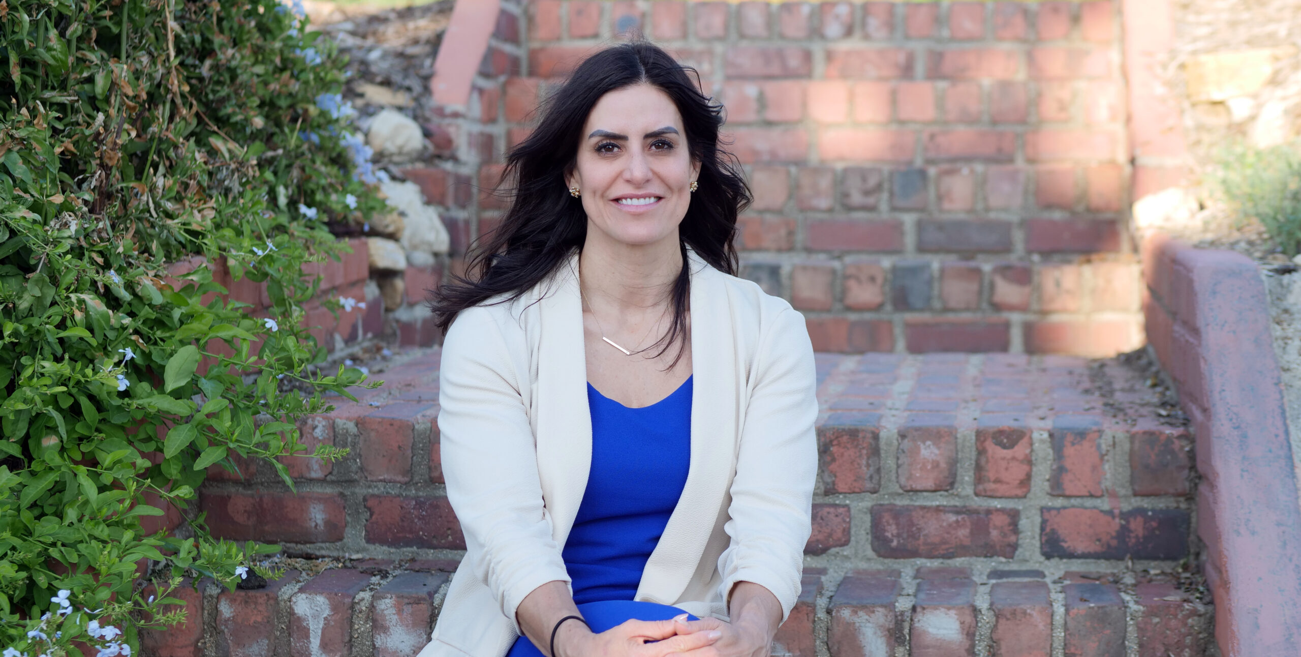 Bail Project Philanthropic Director Kristina Justiniano smiling, sitting on brick steps outside